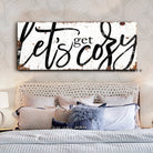 Toe Fish Art “Let’s Get Cozy” farmhouse wall decor sign in rustic white and black, available as a framed canvas or durable metal sign. Warm and inviting master or guest bedroom, living room, lounge, cottage style artwork adds rustic charm and modern country elegance to any space designed for snuggling. Handmade, authentic, heritage quality American-made wall art, perfect for farmhouse, cottage, or rustic industrial style home decorating.