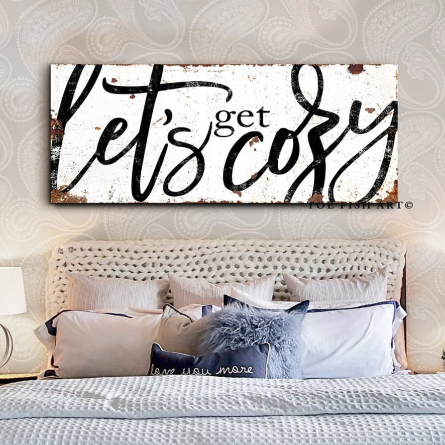 Toe Fish Art “Let’s Get Cozy” farmhouse wall decor sign in rustic white and black, available as a framed canvas or durable metal sign. Warm and inviting master or guest bedroom, living room, lounge, cottage style artwork adds rustic charm and modern country elegance to any space designed for snuggling. Handmade, authentic, heritage quality American-made wall art, perfect for farmhouse, cottage, or rustic industrial style home decorating.