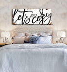 Toe Fish Art “Let’s Get Cozy” farmhouse wall decor sign in rustic white and black, available as a framed canvas or durable metal sign. Warm and inviting master or guest bedroom, living room, lounge, cottage style artwork adds rustic charm and modern country elegance to any space designed for snuggling. Handmade, authentic, heritage quality American-made wall art, perfect for farmhouse, cottage, or rustic industrial style home decorating.