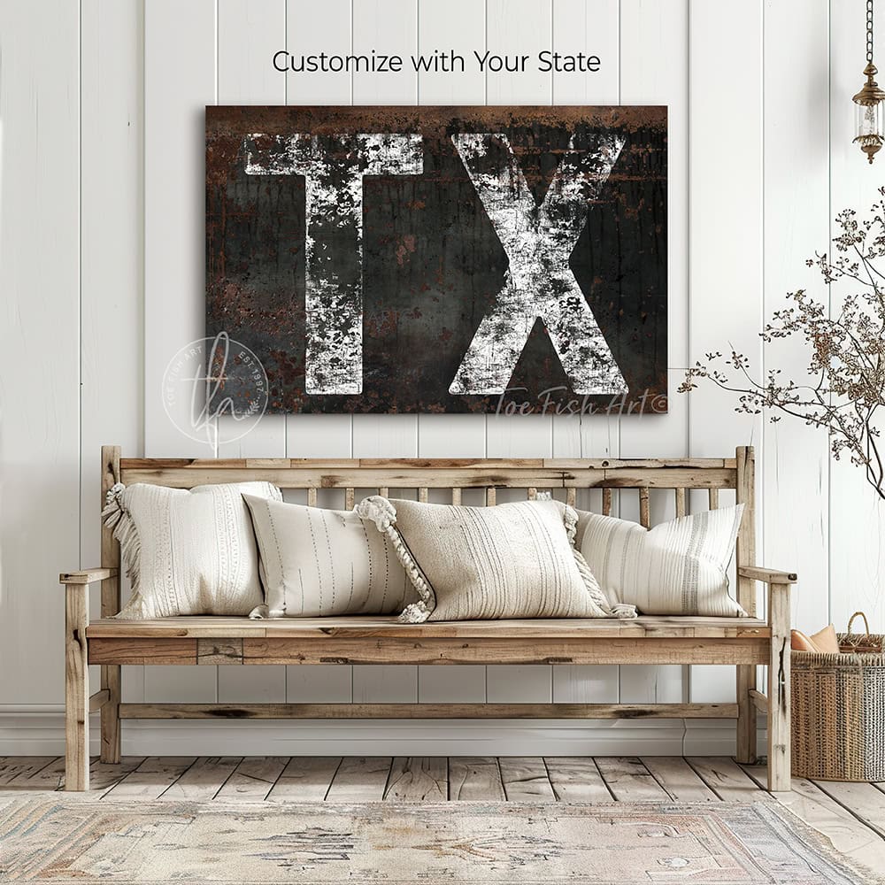 Personalized USA state location wall art featuring your custom two-letter state abbreviation on a dark, distressed industrial farmhouse background with vintage rustic charm and faded white lettering. Be surrounded by decor you LOVE! Choose between premium framed canvas or durable outdoor metal. Toe Fish Art makes artisan wall art with American materials. Proudly Made in the USA, each piece is expertly constructed with genuine craftsmanship, heritage quality, and rustic charm.