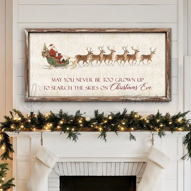 Rustic Christmas wall art featuring Santa Claus in a sleigh pulled by reindeer with the quote “May You Never Be Too Grown Up to Search the Skies on Christmas Eve.” Vintage farmhouse holiday décor perfect for adding nostalgic Christmas charm to your home.