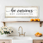 "Be Curious Not Judgmental" invites you to live with intention. This modern farmhouse wall art by Toe Fish Art serves as a reminder to approach life with kindness. Featuring neutral vintage tones that complement any space. Be surrounded by decor you LOVE! Choose premium gallery-stretched canvas or elegant framed canvas. Toe Fish Art makes artisan wall art with American materials. Proudly Made in the USA, each piece is expertly constructed with genuine craftsmanship, heritage quality, and rustic charm.