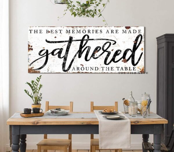 Toe Fish Art's vintage rustic sign "The Best Memories are Made Gathered Around the Table" in framed canvas or outdoor waterproof metal. This unique sign is hand-lettered by the artist, and features a rustic white metal finish with striking charcoal black lettering, embodying a classic and timeless modern farmhouse cottage aesthetic. Available in a large selection of sizes, this handmade decor piece is proudly crafted in the USA, and ships free within the "lower 48" states. Blending rustic primitive country charm with modern cottage farmhouse style, this unique handcrafted artwork is made of durable high-quality framed canvas or outdoor weatherproof solid aluminum metal, making it perfect for incorporating in any remodeling, renovation or decor update project, indoors or outdoors. Proudly made in the USA, each piece is designed to last a lifetime by the artisans at Toe Fish Art. This beautiful sign enhances any decor, adding eye-catching appeal to your space. It’s perfect for your patio, lanai, bar & grill, deck, veranda, dining room, kitchen, or breakfast nook. A splendid reminder of time well spent with family and friends gathered 'round, this artwork fits various styles, including rustic modern farmhouse, cottagecore, vintage, retro, industrial, Americana, primitive, country, coastal, and minimalist. Toe Fish Art is a small family, woman-owned business, creating beautiful decor for almost three decades, since 1997!