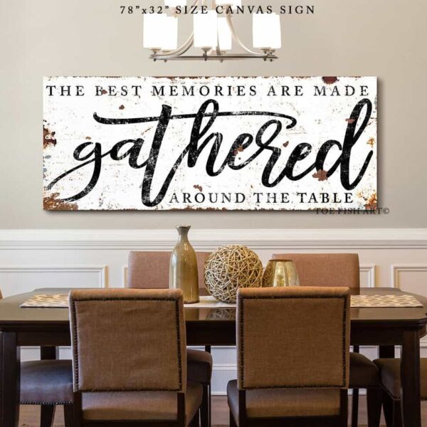 Toe Fish Art's vintage rustic sign "The Best Memories are Made Gathered Around the Table" in framed canvas or outdoor waterproof metal. This unique sign is hand-lettered by the artist, and features a rustic white metal finish with striking charcoal black lettering, embodying a classic and timeless modern farmhouse cottage aesthetic. Available in a large selection of sizes, this handmade decor piece is proudly crafted in the USA, and ships free within the "lower 48" states. Blending rustic primitive country charm with modern cottage farmhouse style, this unique handcrafted artwork is made of durable high-quality framed canvas or outdoor weatherproof solid aluminum metal, making it perfect for incorporating in any remodeling, renovation or decor update project, indoors or outdoors. Proudly made in the USA, each piece is designed to last a lifetime by the artisans at Toe Fish Art. This beautiful sign enhances any decor, adding eye-catching appeal to your space. It’s perfect for your patio, lanai, bar & grill, deck, veranda, dining room, kitchen, or breakfast nook. A splendid reminder of time well spent with family and friends gathered 'round, this artwork fits various styles, including rustic modern farmhouse, cottagecore, vintage, retro, industrial, Americana, primitive, country, coastal, and minimalist. Toe Fish Art is a small family, woman-owned business, creating beautiful decor for almost three decades, since 1997!