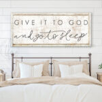 Toe Fish Art's original Faith-based bedroom wall decor sign featuring the popular quote 'Give it to God and Go to Sleep.' Available in color options of timeworn white or lightly distressed white, this hand-lettered original design comes in either framed canvas or solid aluminum metal. A comforting, clever and popular saying, perfect for creating a serene, peaceful atmosphere in your master bedroom or guest room. Built to last with genuine craftsmanship, this relevant decor adds rustic charm and heritage quality to any space. Made in the USA with durable, authentic materials for a beautiful and meaningful theme. Rustic country charm meets modern minimalist farmhouse wall decor handcrafted in durable high-quality framed canvas or sleek and solid aluminum metal, handmade in the USA from start to finish! Beautiful, stylish and timeless wall decor. Handcrafted in the USA by ToeFishArt, and built to last a lifetime by the Toe Fish Art family artisans. This beautiful original artwork adds unique eye-catching decor to any bedroom or lounging and relaxation space. Perfect for your master bedroom, guest rooms, outdoor lounge napping space or hammock area. This sign is a happy playful reminder of Christian faith and God's love. Original, custom, personalized wall decor signs. Canvas, Wood or Metal. Rustic modern farmhouse, cottagecore, vintage, retro, industrial, Americana, primitive, country, coastal, minimalist. Toe Fish Art is a USA small family woman owned business making beautiful decor since 1997.