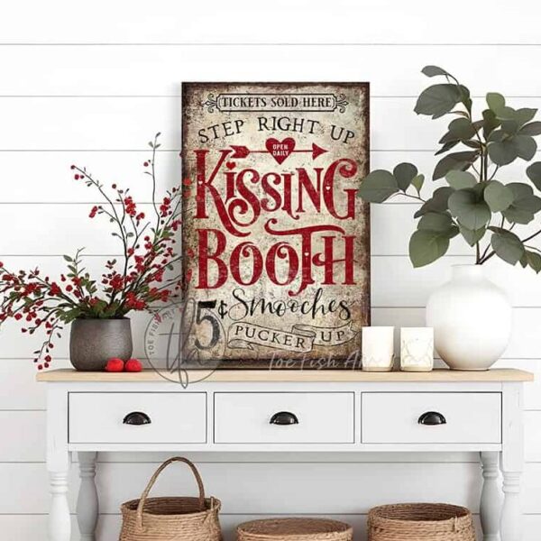Toe Fish Art’s vintage cottage-style wall art showcases a rustic Kissing Booth sign, perfect for Valentine’s Day. Inspired by old-time fairs and carnivals, this vertical piece features a charming design advertising “5-cent smooches” in a distressed red, white, and black color palette for an authentic, nostalgic touch. This wall decor is available in numerous sizes from small to huge, and several material choices suitable for your space. Blending rustic primitive country charm with cottage farmhouse style, this handcrafted artwork is available in durable high-quality framed canvas or outdoor weatherproof solid aluminum metal. Proudly made in the USA, each piece is designed to last a lifetime by the artisans at Toe Fish Art. This beautiful artwork enhances any decor, and makes the perfect Valentine Gift, adding eye-catching appeal indoors or outdoors. It’s perfect for display in a porch, entryway, patio, lanai, deck, veranda, living room, fireplace hearth or mantel, dining room, or bedroom, or as a shelf sitter. A special reminder of the season of love, this artwork fits various styles, including rustic modern farmhouse, cottagecore, vintage, retro, industrial, Americana, primitive, country, coastal, and minimalist. Toe Fish Art is a small family, woman-owned business, creating beautiful decor for almost three decades, since 1997!