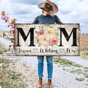 Toe Fish Art's unique, artisan-made Vintage Flower Bouquet "MOM" sign personalized with hand-lettered cursive family names to fit your style. This custom wall art is available as a wood-framed canvas with choice of framing colors, or outdoor waterproof metal, showcasing a worn rustic white background with bold black lettering and a beautiful painting of red, pink, and yellow roses. An ideal Mother's Day gift or any special occasion to celebrate Mom! Expertly made with American-sourced materials. This premium, handcrafted piece features a timeless aesthetic. Built to last with genuine craftsmanship, it adds rustic charm and heritage quality to any space. Made in the USA with durable, authentic materials for a beautiful and meaningful display. Rustic Cottagecore Country and Modern Farmhouse wall decor handcrafted in durable high-quality framed canvas or outdoor weatherproof solid aluminum metal, handmade in the USA from start to finish! Beautiful, stylish and timeless floral wall decor painting. Handcrafted in the USA by ToeFishArt, and built to last a lifetime by the Toe Fish Art family artisans. This beautiful original artwork adds unique eye-catching decor indoors or outdoors. Add instant outdoor curb appeal to your home! Perfect for your porch, entryway, patio, lanai, deck, garden, courtyard, gazebo, pergola, living room, fireplace hearth or mantel, wall hanging or shelf sitter, dining room or bedroom. This painting is a beautiful reminder of the gift of Mom's love to celebrate her for Mother's Day and all-year long. Original, custom, personalized wall decor signs. Canvas, Wood or Metal. Rustic modern farmhouse, cottagecore, vintage, retro, industrial, Americana, primitive, country, coastal, minimalist. Toe Fish Art is a USA small family woman owned business making beautiful decor since 1997.