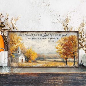 Toe Fish Art's Faith-inspired wall art featuring Psalm 107:1 ‘Give thanks to the Lord for He is good, His love endures forever’ hand-lettered on a rustic country church scene surrounded by golden autumn trees landscape painting. Handmade in the USA and constructed in framed canvas or waterproof outdoor metal. Vintage fall colors, perfect for Christian home décor, Thanksgiving, or seasonal autumn cottagecore decor.