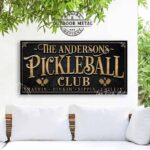 Toe Fish Art’s personalized "Pickleball Club” sign features the phrase "Smashin' Dinkin' Sippin' Chillin’" in rustic gold style lettering on a vintage slate black background. Available as a beautiful framed canvas sign or durable and sleek outdoor metal sign, this custom wall art decor adds humor and charm to your game space or post-play lounge area. Made in America and built to last, perfect for pickleball lovers, sports decor, and custom man cave or backyard court accents. This premium printed sign showcases a detailed, original design ideal for upgrading your sports bar, game room, court-side seating, outdoor entertaining space, or backyard decor. Customized sign, personalized with family name or favorite saying and custom wording options. Available in a huge array of sizes, Toe Fish Art's artisan-made wall decor is expertly made in America with American-sourced materials. This high-end, handcrafted piece can be customized to fit your style! Built to last with genuine craftsmanship, this heirloom decor adds rustic cottage charm and heritage quality to any space. Made in the USA with durable, authentic materials for a beautiful and meaningful display to last year after year. Modern Farmhouse Cottagecore wall decor handcrafted in durable high-quality framed canvas or indoor-outdoor weatherproof solid aluminum metal, handmade in the USA from start to finish! Beautiful, stylish and timeless wall decor artwork. Handmade in the USA by ToeFishArt, and built to last a lifetime by the Toe Fish Art family artisans. This beautiful original artwork adds unique eye-catching decor indoors or outdoors. Perfect for your game room, man cave, sports bar post-game lounge, basement bar, garage bar, patio, lanai, deck, or any outdoor living space. This special decoration is a fun way to celebrate your favorite game with friends. Original, custom, personalized wall decor signs. Canvas, Wood or Metal. Rustic modern farmhouse, cottagecore, vintage, retro, industrial, Americana, primitive, country, coastal, minimalist. Toe Fish Art is a USA small family woman owned business making beautiful decor since 1997.