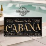 Welcome to the Cabana personalized wall sign by Toe Fish Art in vintage black with rustic gold lettering, available in framed canvas or waterproof outdoor metal, with custom family name and established year, and fun sayings like Relax & Unwind, Sipping-Grilling-Chilling—charming pool, spa, beach, lake, or patio decor handmade in the USA. Ideal for enhancing your outdoor summer decor. Built to last with genuine craftsmanship, this authentic sign adds classic cottage charm and heritage quality to any space.